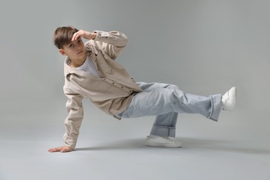 Photo of Boy in stylish clothes dancing on light grey background