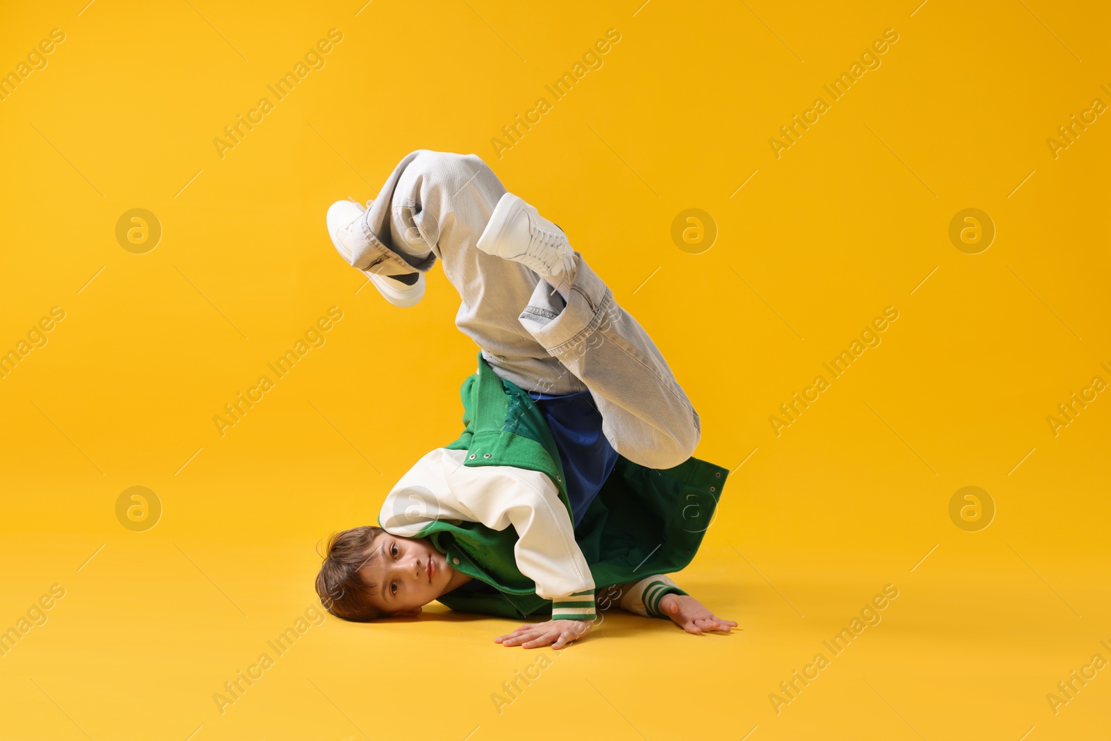 Boy in stylish clothes dancing on orange background Photo of Boy in stylish clothes dancing on orange background