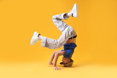 Photo of Boy in stylish clothes dancing on orange background