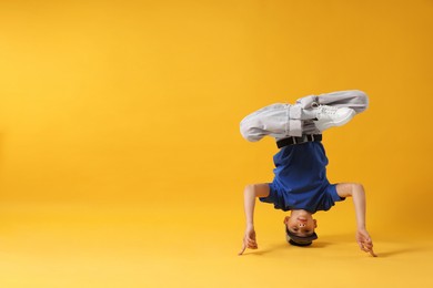 Photo of Boy in stylish clothes dancing on orange background, space for text