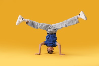 Photo of Boy in stylish clothes dancing on orange background