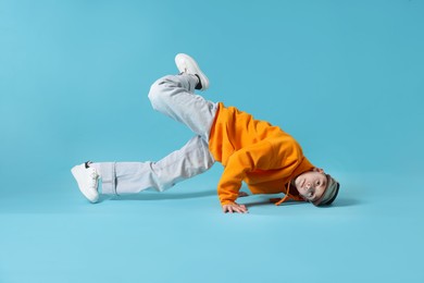 Photo of Boy in stylish clothes dancing on light blue background