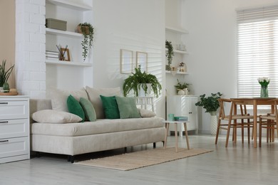 Photo of Comfortable sofa, table, chairs and green houseplants indoors. Interior design