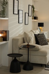 Photo of Comfortable sofa, nesting tables and different decor indoors. Interior design