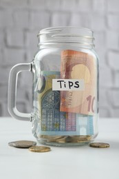 Photo of Tips jar with money on white table