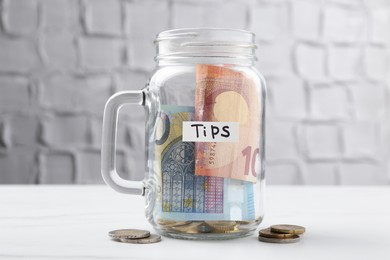 Photo of Tips jar with money on white marble table