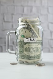 Photo of Tips jar with money on white marble table