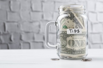 Photo of Tips jar with money on white marble table, space for text