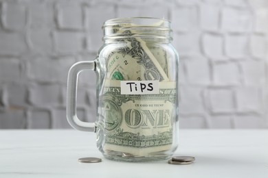 Photo of Tips jar with money on white marble table