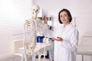 Photo of Doctor pointing at parts of human skeleton model in clinic
