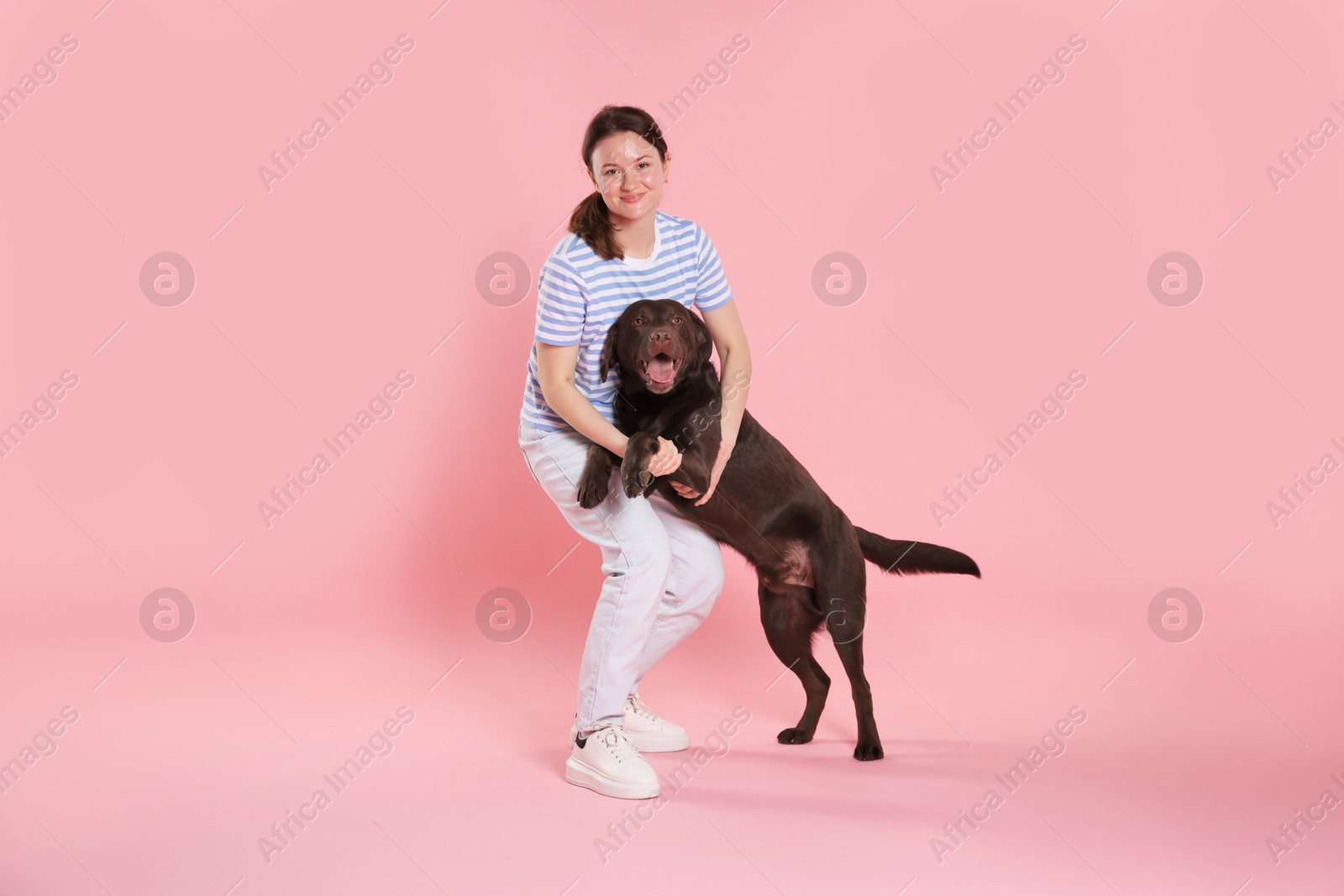 Animal training. Woman with her cute dog on pink background Photo of Animal training. Woman with her cute dog on pink background