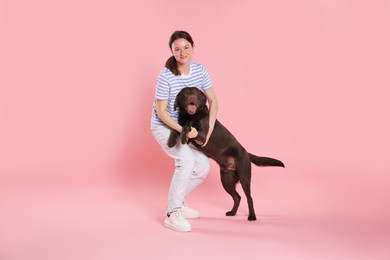 Photo of Animal training. Woman with her cute dog on pink background