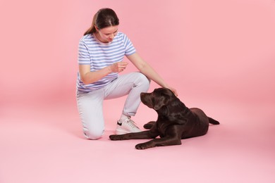 Photo of Animal training. Woman with her cute dog on pink background