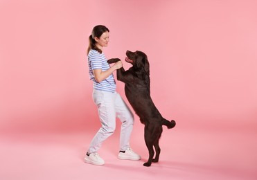 Photo of Animal training. Woman with her cute dog on pink background