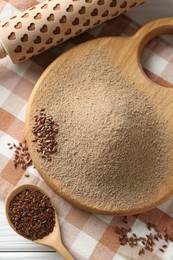 Photo of Flaxseed flour, rolling pin and spoon on table, flat lay