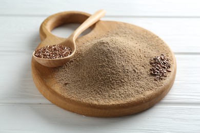 Photo of Flaxseed flour and spoon with seeds on white wooden table, closeup
