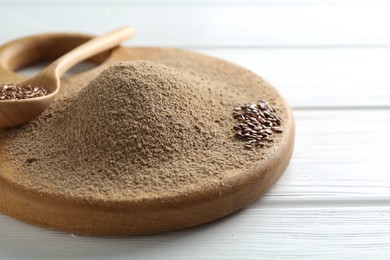 Photo of Flaxseed flour and spoon with seeds on white wooden table, closeup