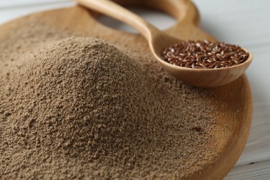 Photo of Flaxseed flour and spoon with seeds on table, closeup