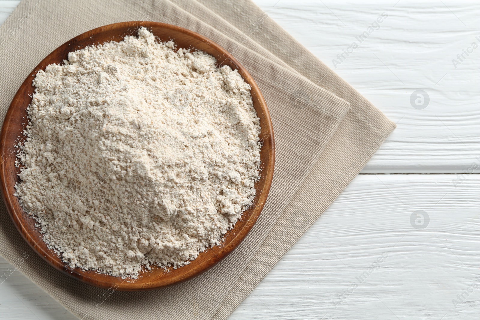 Photo of Flour on white wooden table, top view. Space for text
