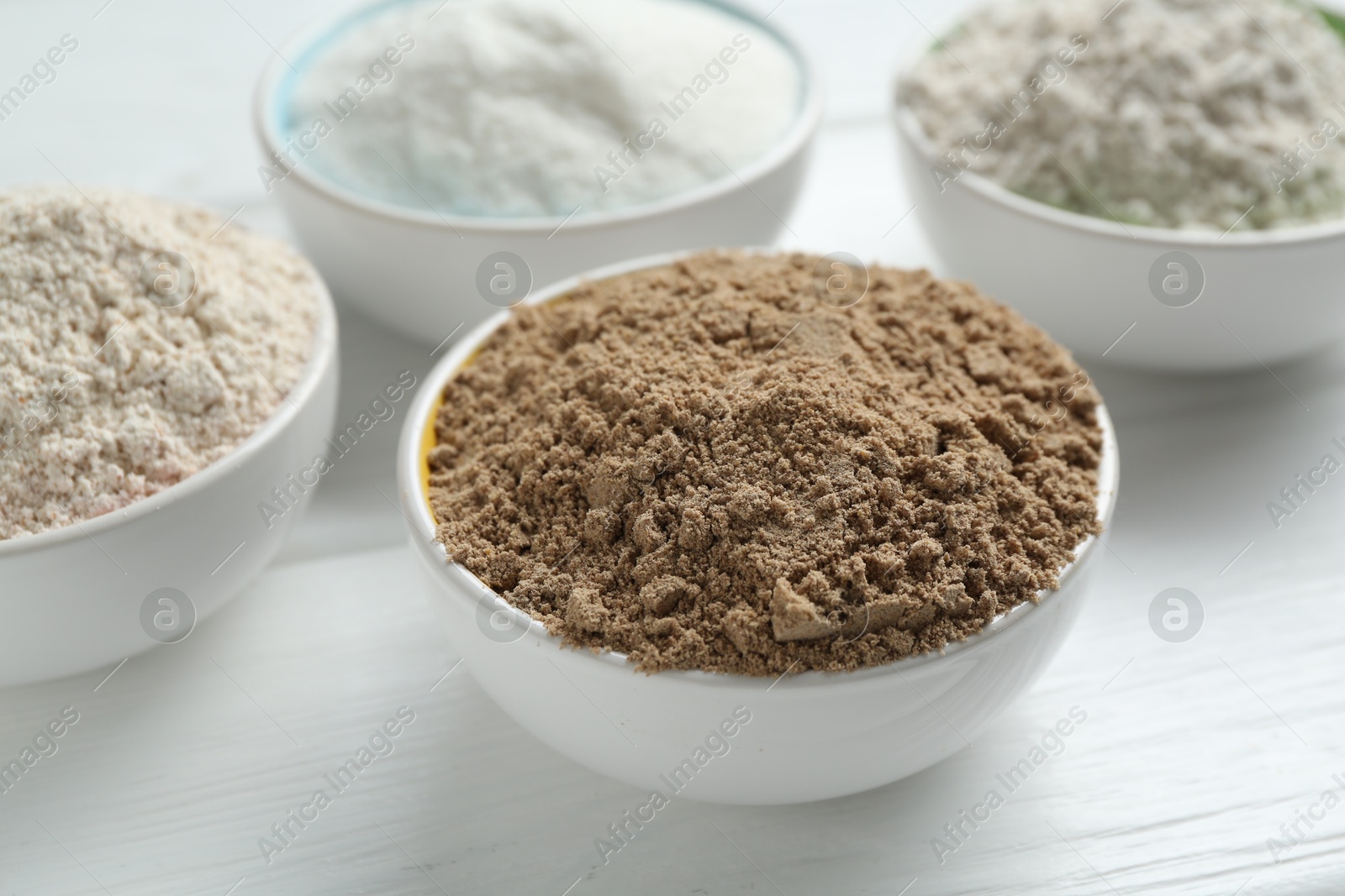 Different types of flour in bowls on white wooden table, closeup Photo of Different types of flour in bowls on white wooden table, closeup