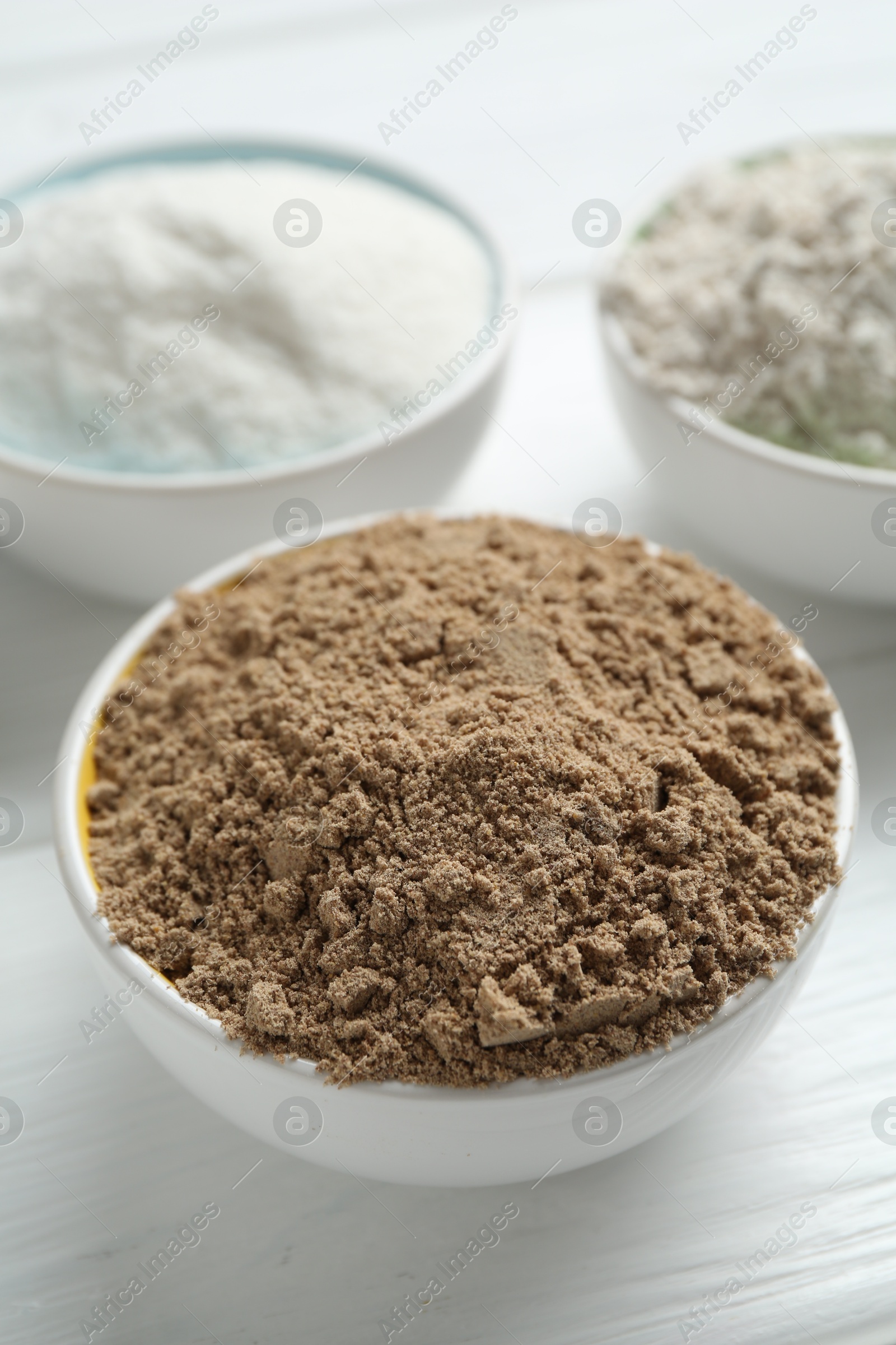 Different types of flour in bowls on white wooden table, closeup Photo of Different types of flour in bowls on white wooden table, closeup