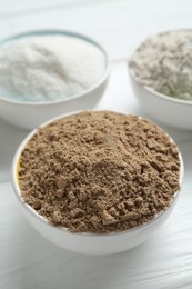 Photo of Different types of flour in bowls on white wooden table, closeup