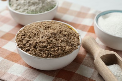 Photo of Different types of flour in bowls and scoop on table, closeup