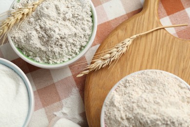Photo of Different types of flour in bowls and spikes on table, flat lay