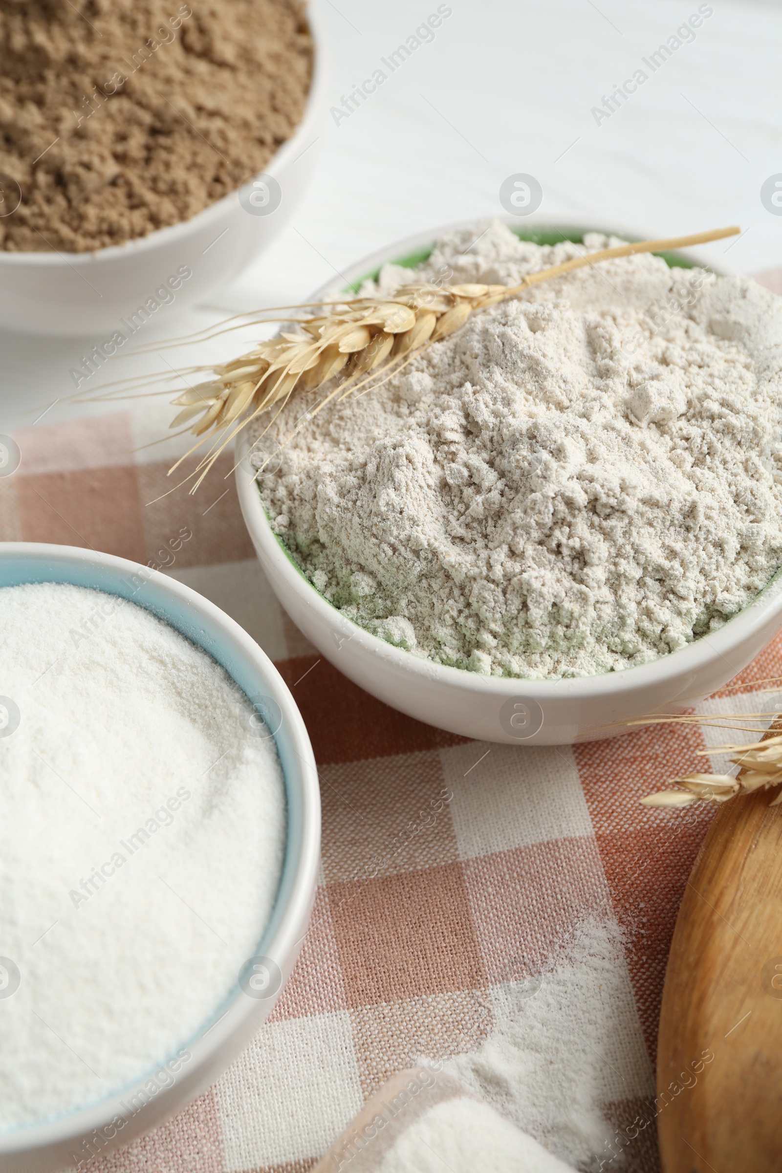 Different types of flour in bowls and spike on table, closeup Photo of Different types of flour in bowls and spike on table, closeup
