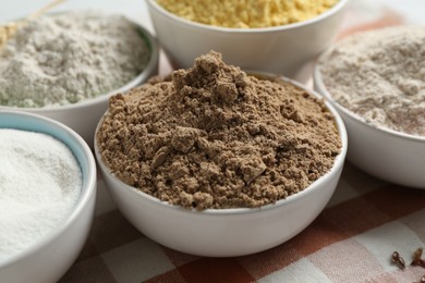 Photo of Different types of flour in bowls on table, closeup