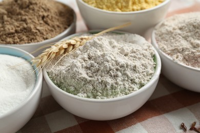 Photo of Different types of flour in bowls on table, closeup