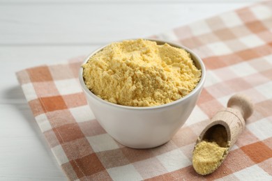 Photo of Corn flour in bowl and scoop on white table, closeup