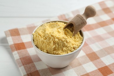 Photo of Corn flour in bowl and scoop on white table, closeup