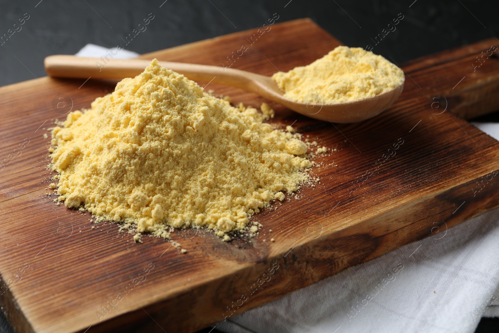 Pile of corn flour and spoon on black table, closeup Photo of Pile of corn flour and spoon on black table, closeup