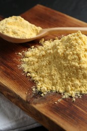 Photo of Pile of corn flour and spoon on table, closeup