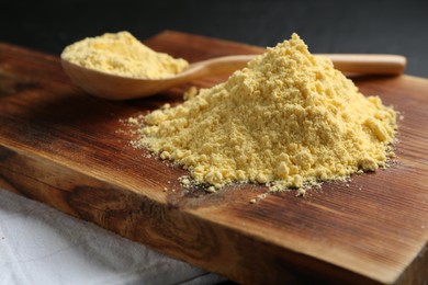 Photo of Pile of corn flour and spoon on table, closeup