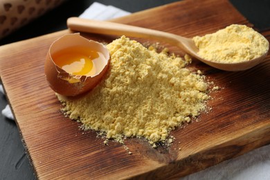 Photo of Pile of corn flour, spoon and broken egg on table, closeup