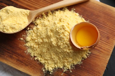Photo of Pile of corn flour, spoon and broken egg on table, top view