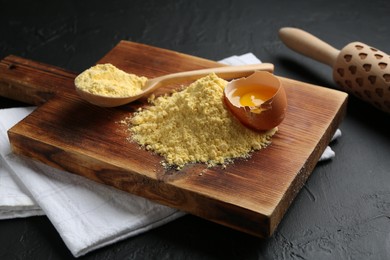 Photo of Pile of corn flour, broken egg and rolling pin on table, closeup