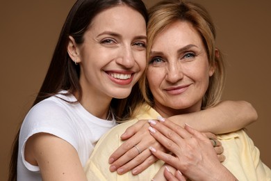 Photo of Woman hugging her mother on light brown background