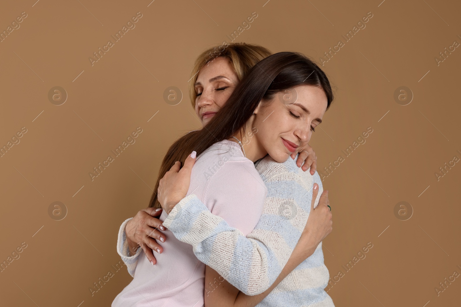 Mother and daughter hugging on beige background Photo of Mother and daughter hugging on beige background