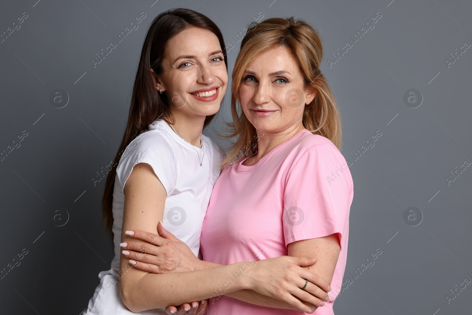 Mother and daughter hugging on grey background Photo of Mother and daughter hugging on grey background