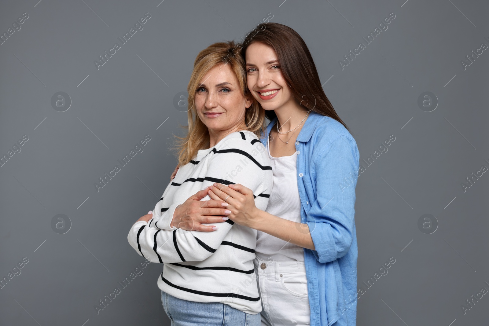 Mother and daughter hugging on grey background Photo of Mother and daughter hugging on grey background
