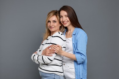 Photo of Mother and daughter hugging on grey background