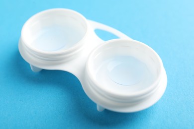 Photo of Contact lenses in case on light blue background, closeup