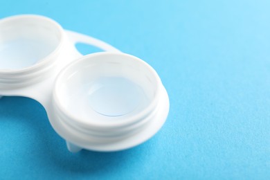 Photo of Contact lenses in case on light blue background, closeup. Space for text