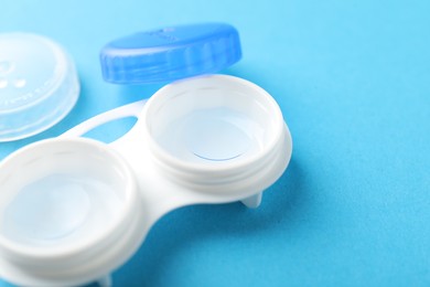 Photo of Contact lenses in case on light blue background, closeup. Space for text