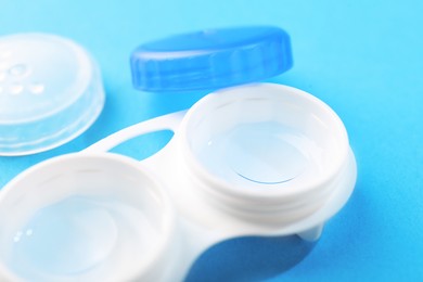 Photo of Contact lenses in case on light blue background, closeup