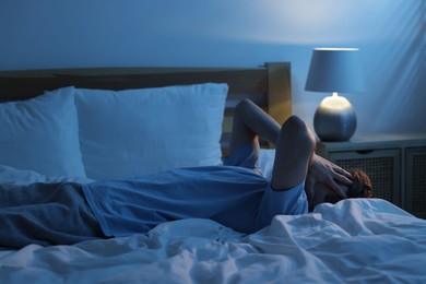 Photo of Frustrated man suffering from insomnia on bed indoors