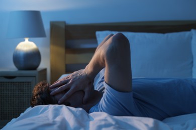 Photo of Frustrated man suffering from insomnia on bed indoors